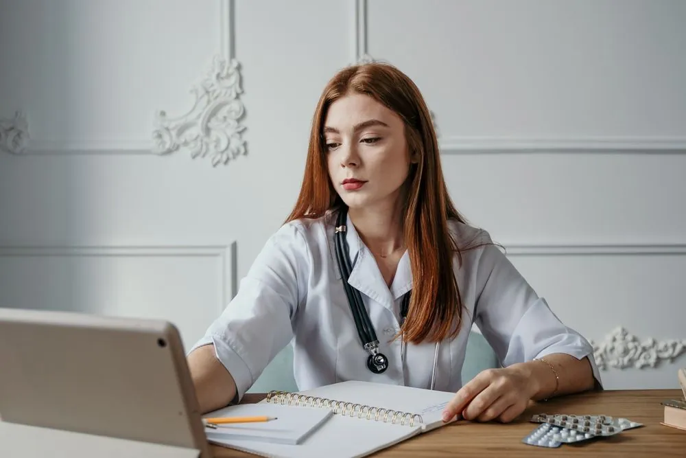 Une professionnelle de santé consulte une tablette à son bureau.